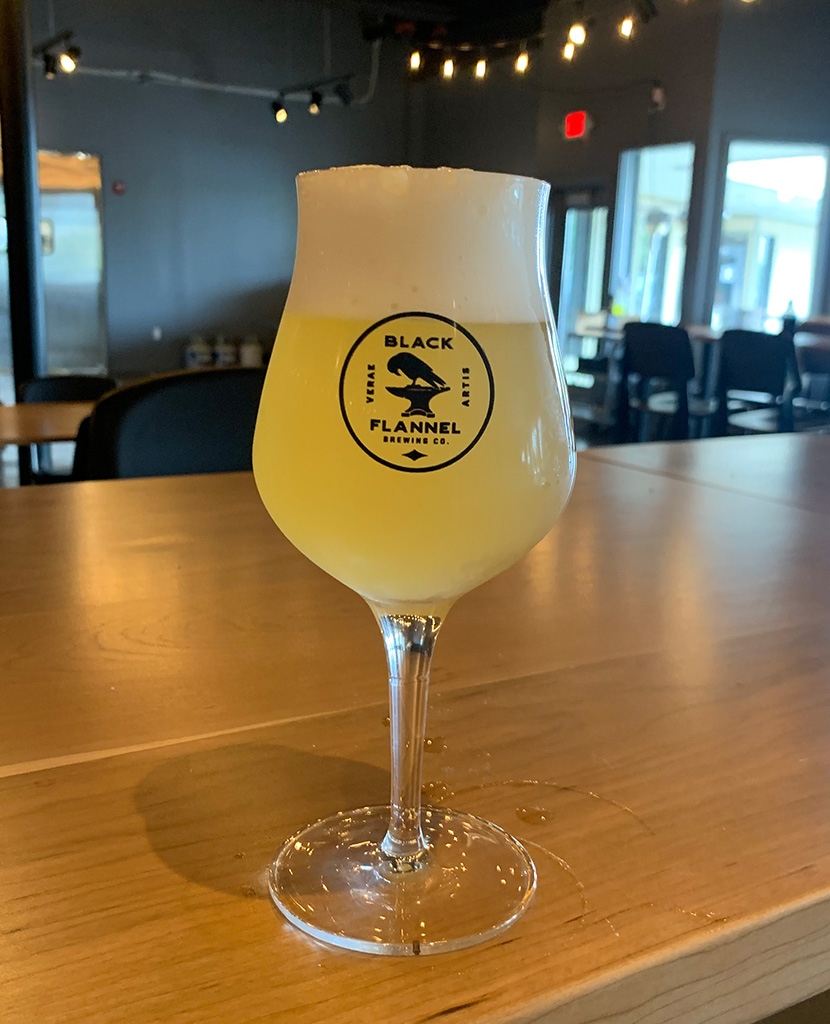 Pale Berliner Weisse beer with a white foam head in a tall glass at Black Flannel.